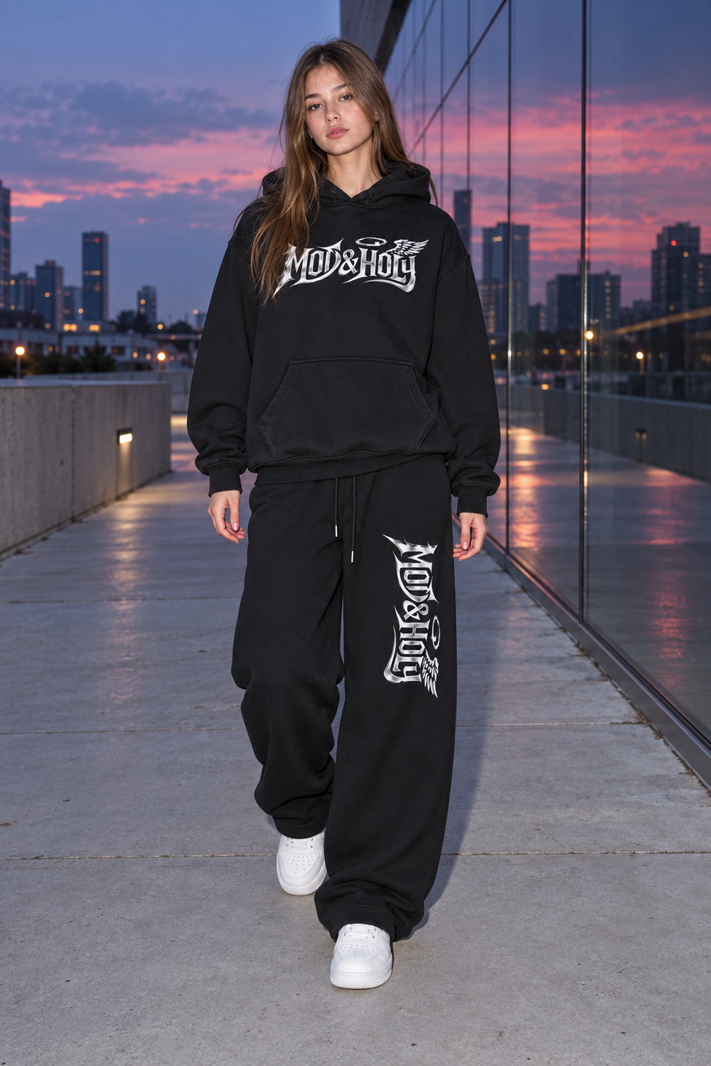Full-length young adult in the chrome wing-and-halo hoodie and matching wide-leg graphic pants.